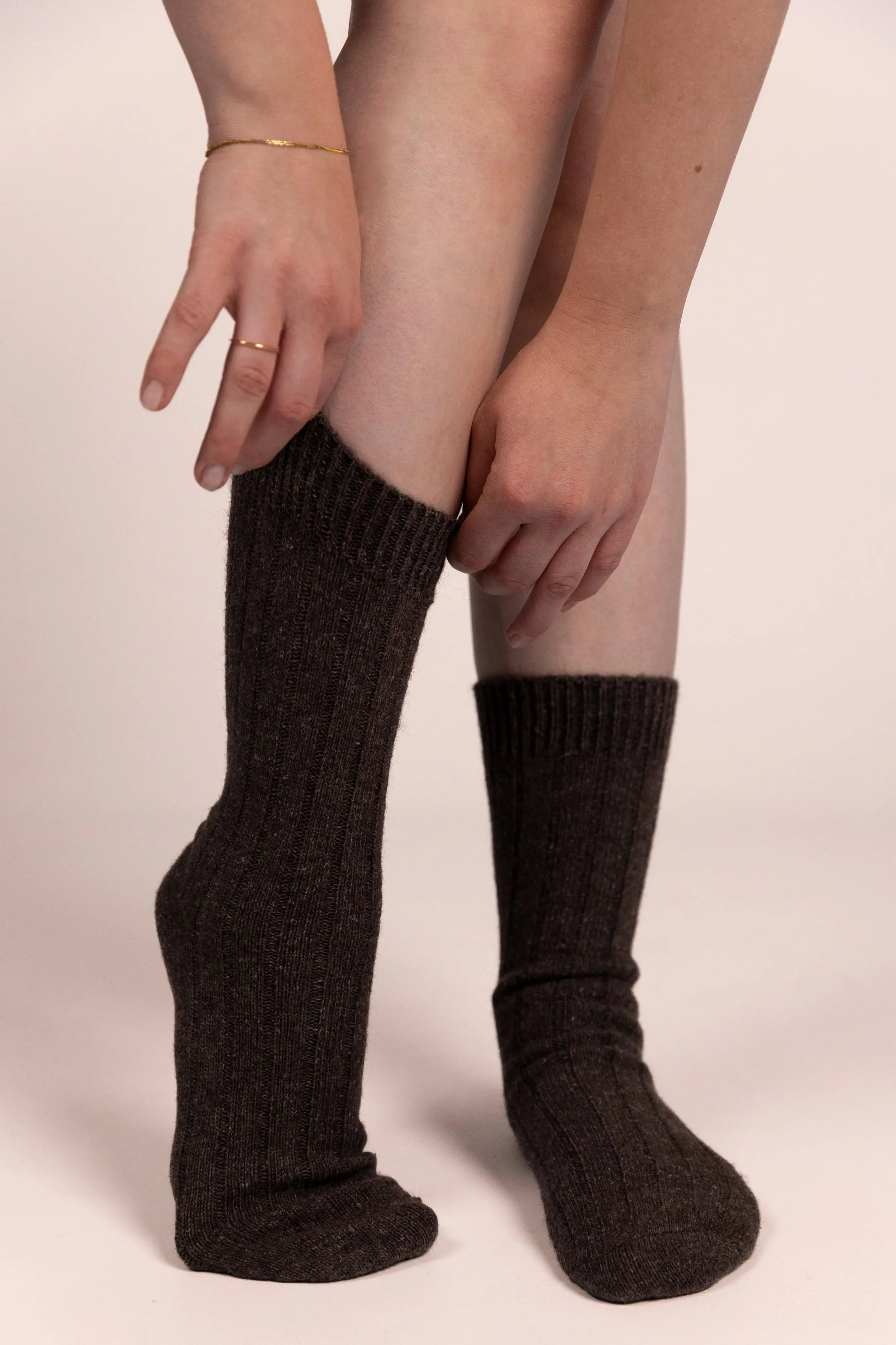 Person wearing dark brown cashmere socks on a plain background