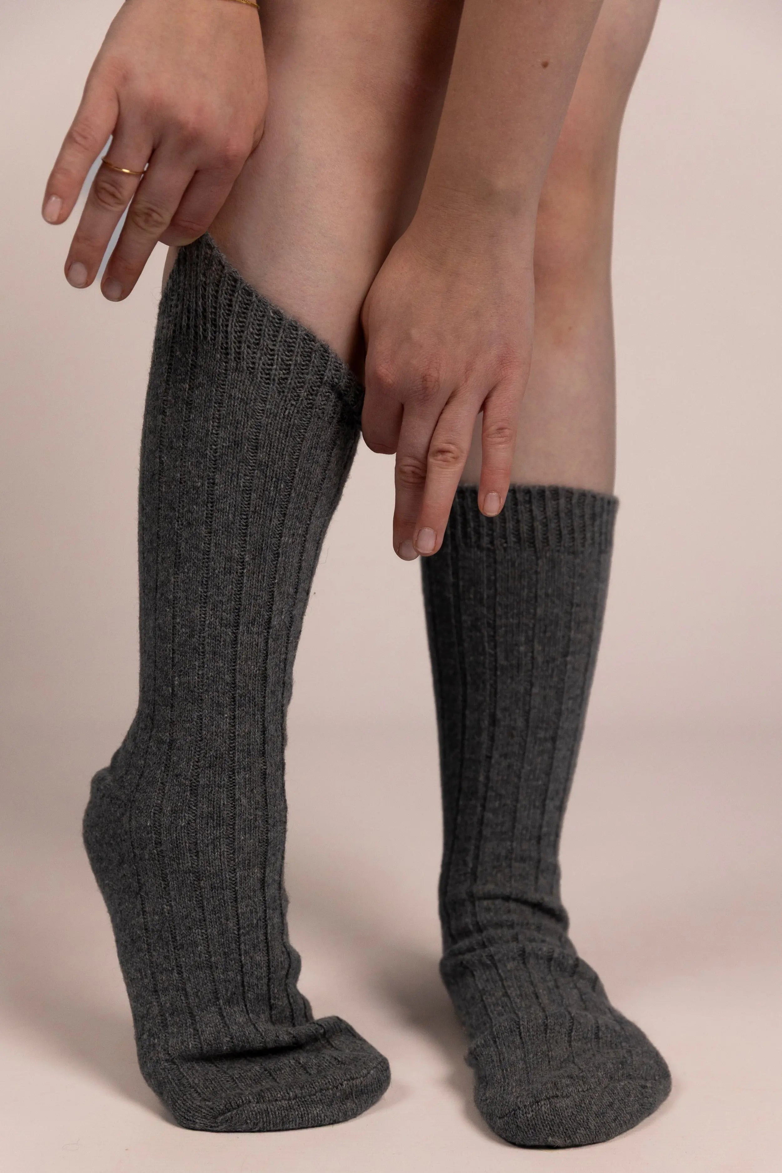 Person wearing dark gray cashmere socks on a plain background
