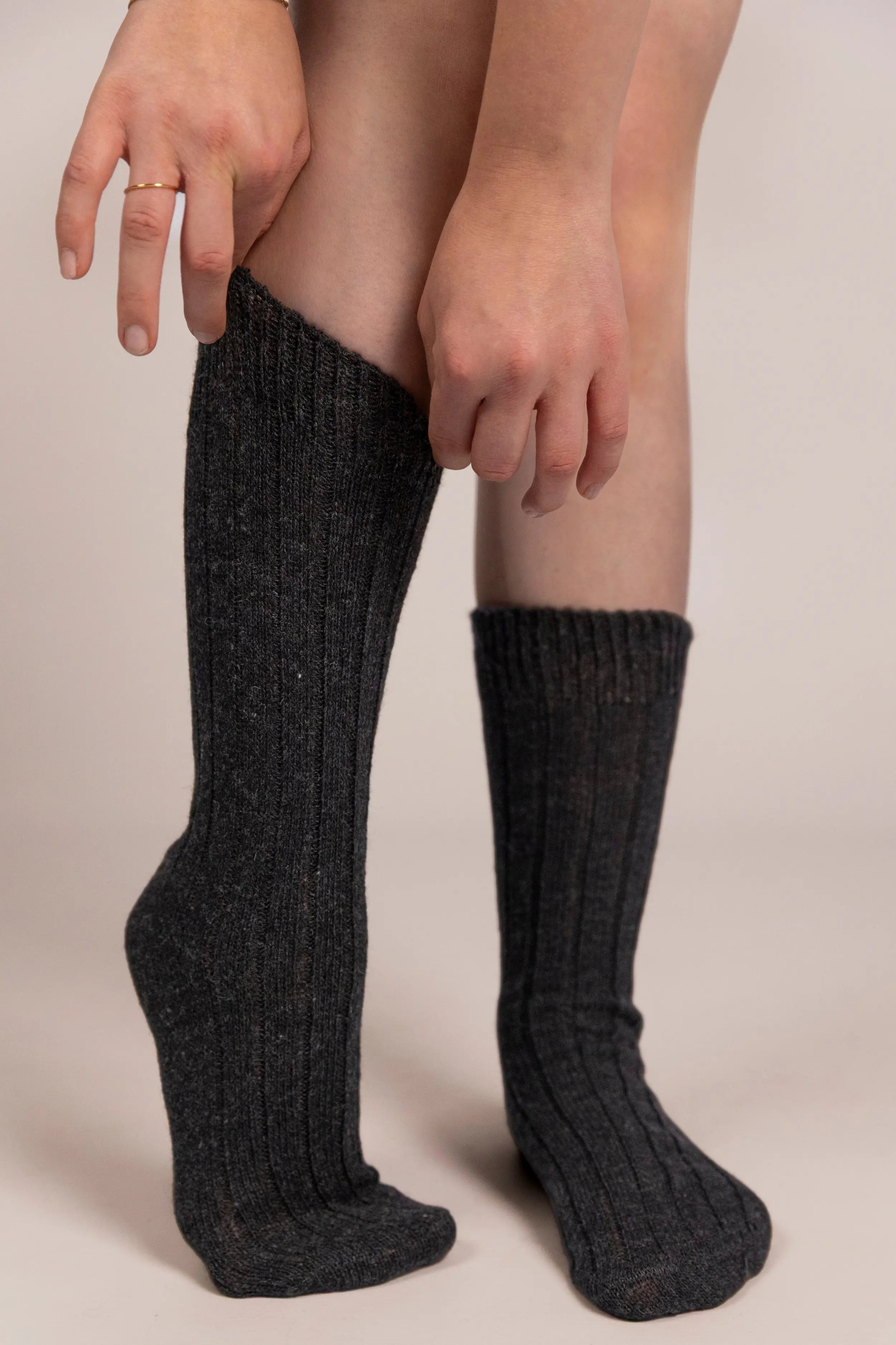 Person wearing anthracite cashmere socks on a plain background