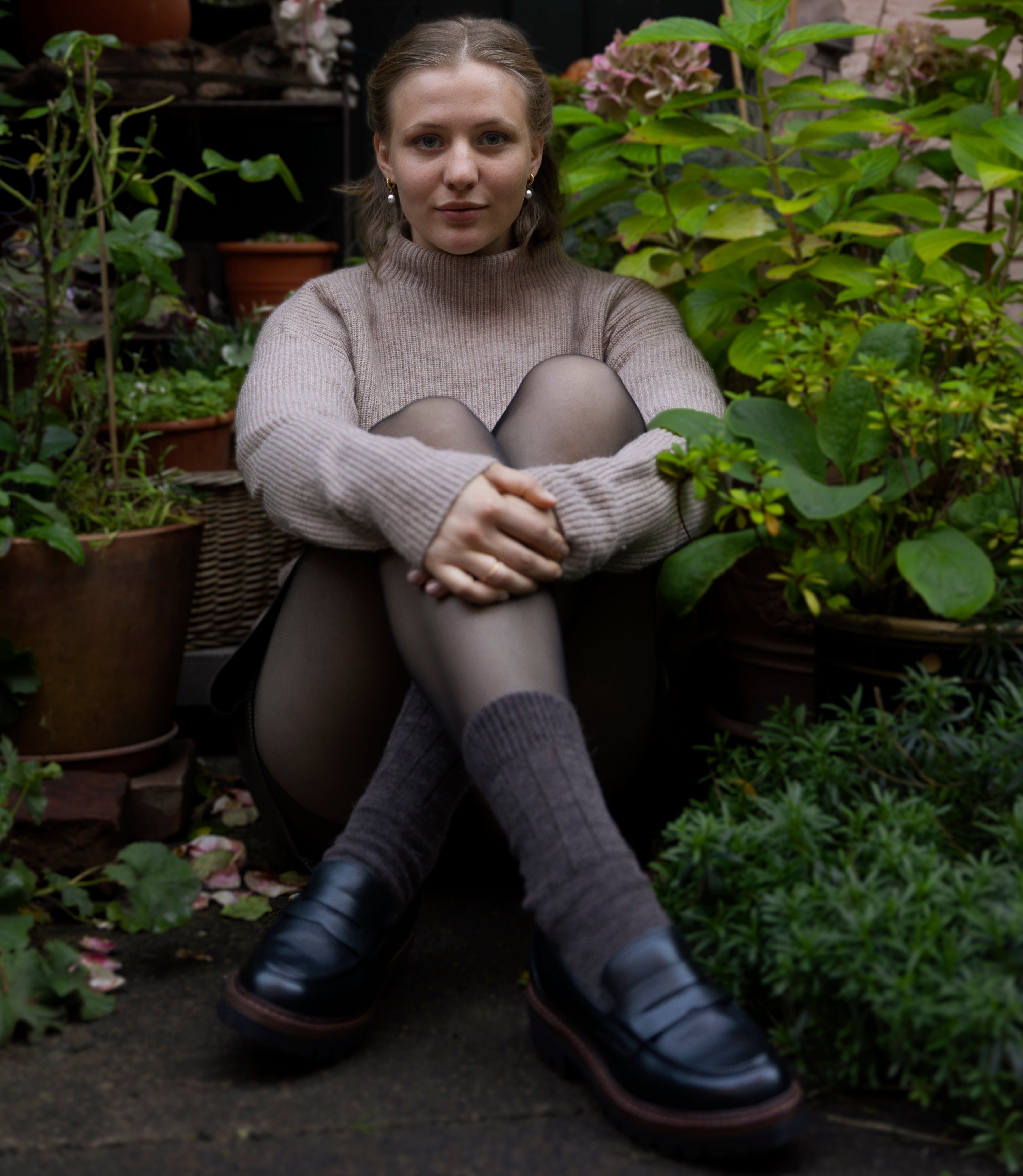 Woman sitting among plants in a garden setting