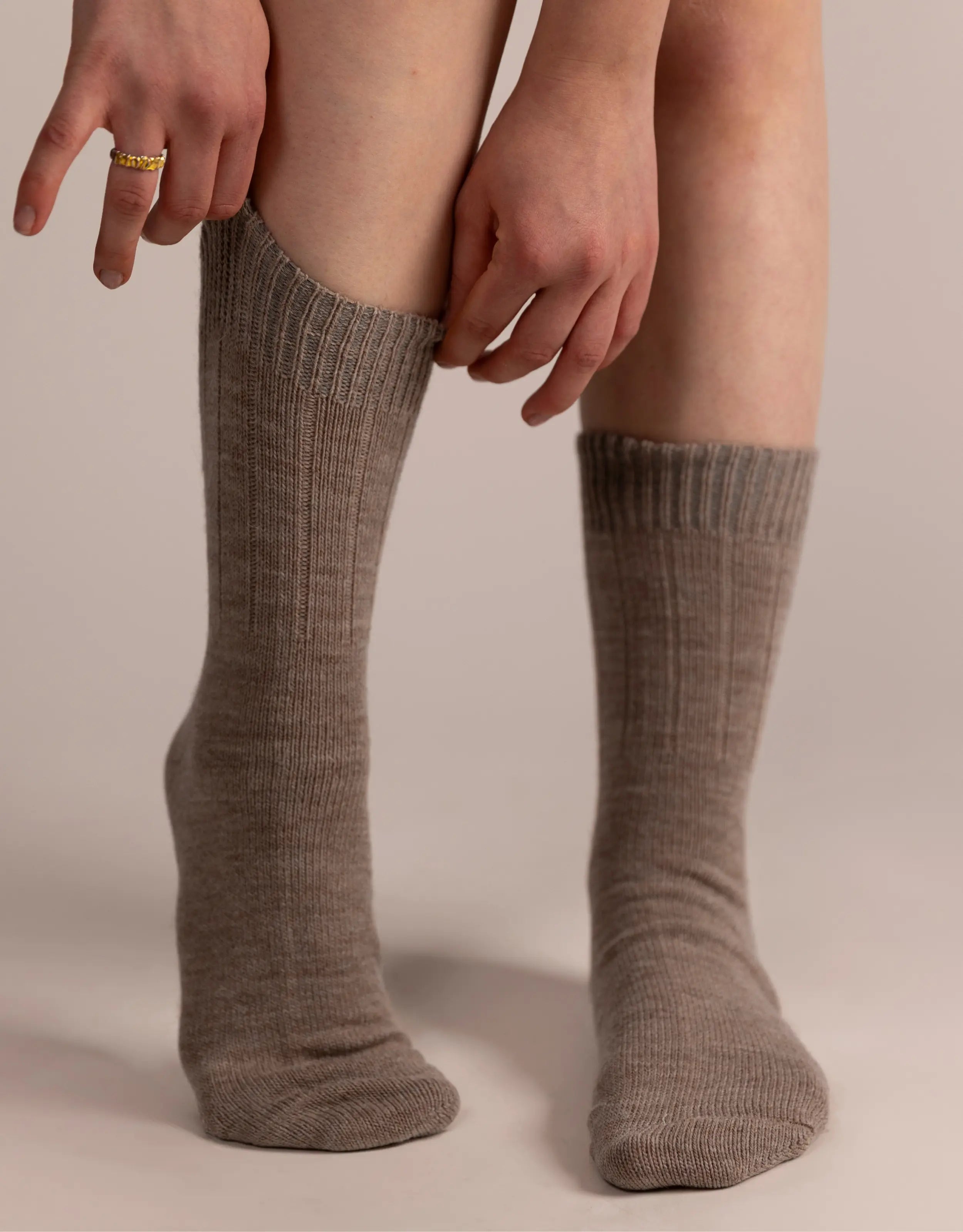 Brown knee-high socks worn by a person on a beige background